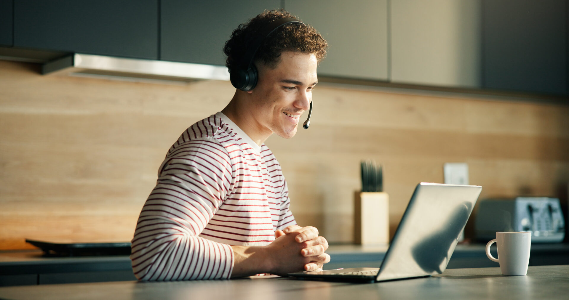 Headset, laptop and happy man in kitchen for remote work, tech support or online assistance. Computer, freelancer and IT consultant in home for help with software hotline, advice or customer service