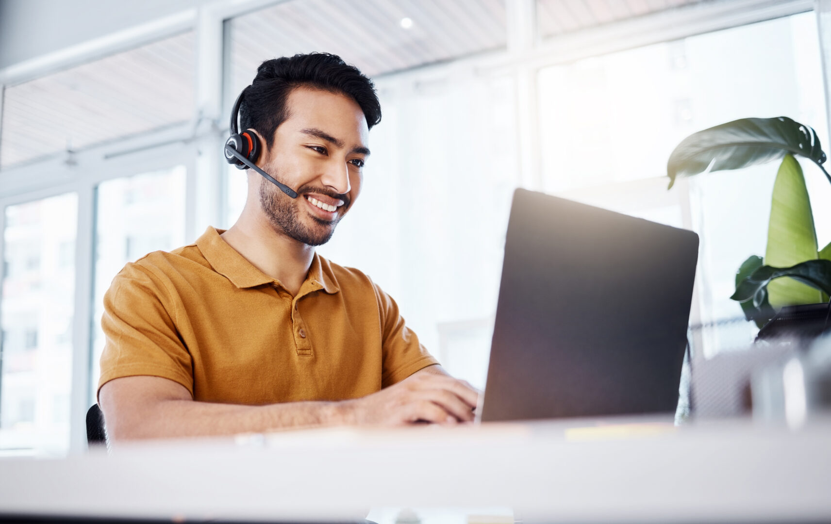 Laptop, man and customer support consultant in office doing research on a crm strategy. Professional, smile and male call center or telemarketing agent working on an online consultation with computer