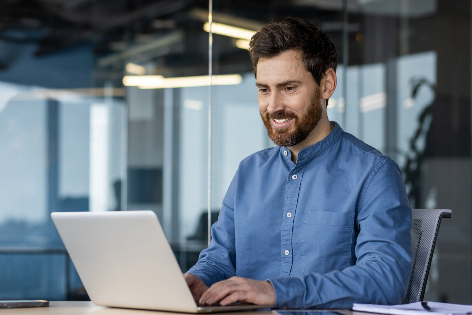 Smiling businessman using laptop in modern office space