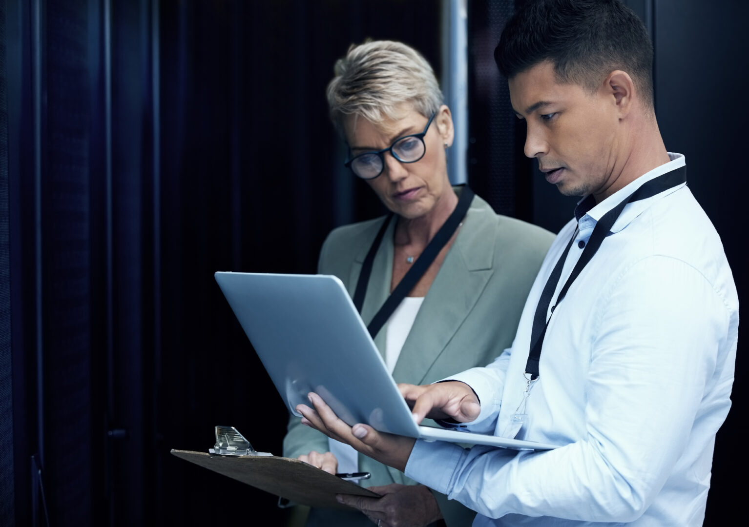 Data center, people and computer engineer with clipboard, collaboration and programming. Mature woman, analytics and technician with hardware, security or maintenance for system update in server room